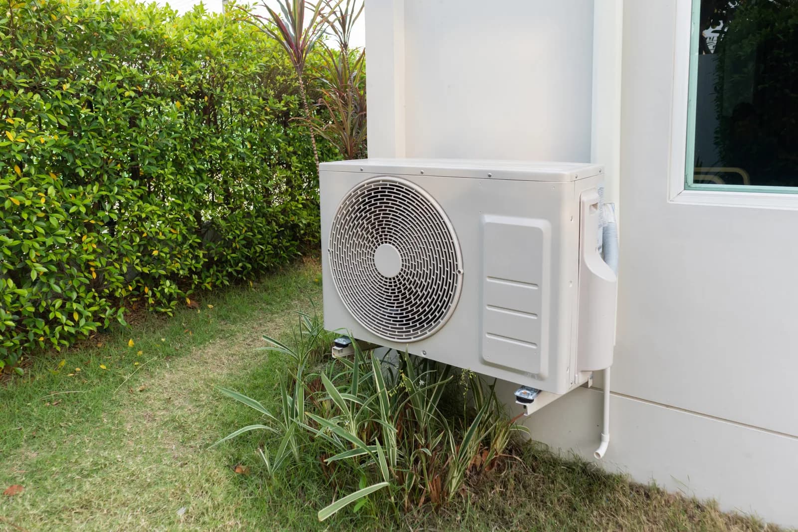 Unité extérieure de pompe à chaleur air-eau installée le long d'une maison